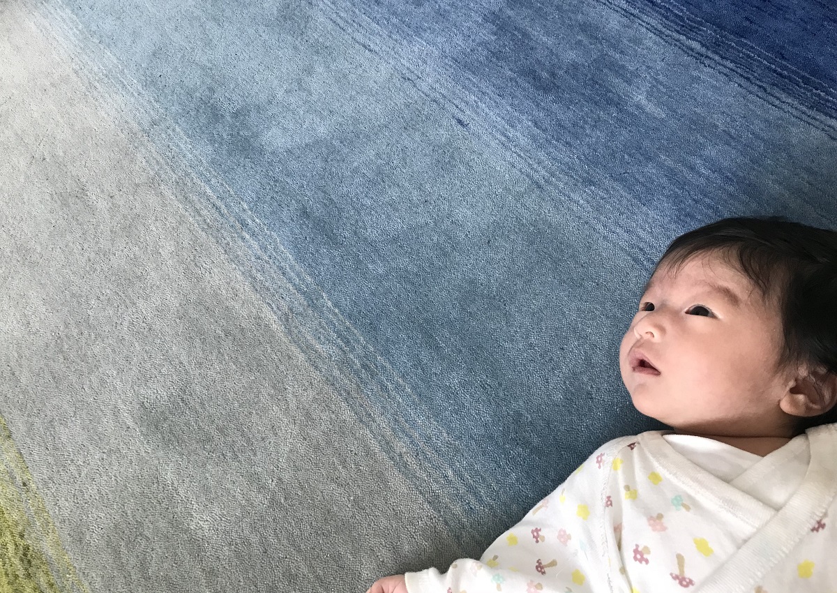 ふわふわの絨毯の上に寝転ぶ赤ちゃん