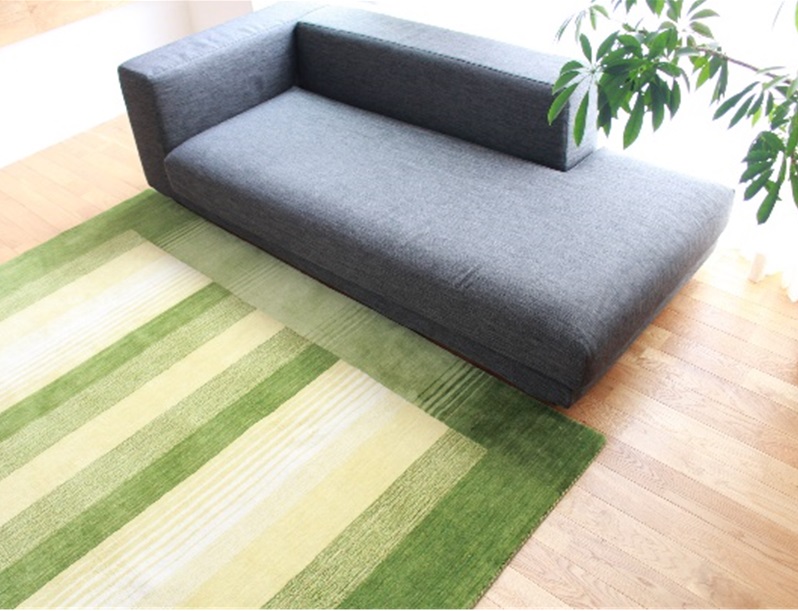 緑色の絨毯がグレーのソファの前に敷いてある様子