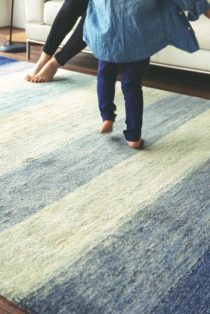 青い手織りの絨毯の上で歩く子供