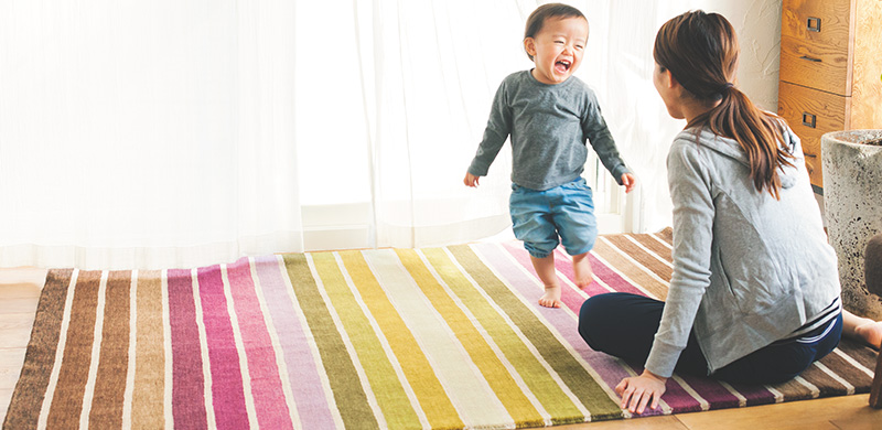 カラフルな絨毯の上で子供が笑っている様子
